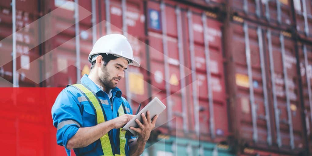 worker looking at his ipad in front of cargo